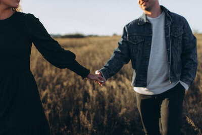 Couple holding hands and walking through a field in Scottsdale