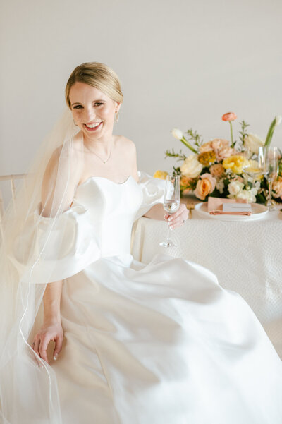 bride sits at table with florals