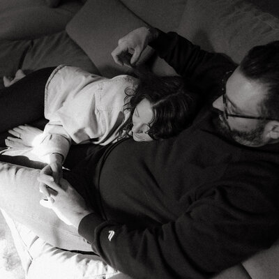 couples snuggling on couch holding hands during in-home engagement session columbia missouri