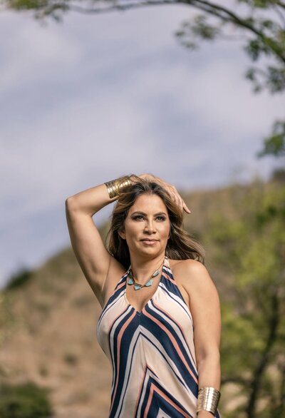 Mayra Menjivar outdoors with a striped dress and gold bracelet