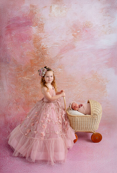 Newborn baby girl and her big sister dressed in pink