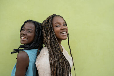 Girls back to back in front of green background