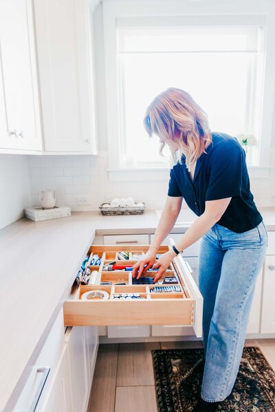 A home organizer placing items within a drawer