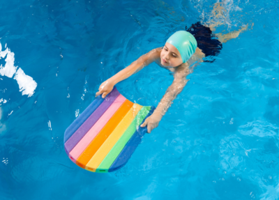 A boy learns to swim with determination, using a float board for support and guidance