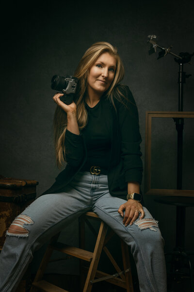 Confident  self portrait of a woman holding a camera in a Sollentuna Portrait Studio by Helena Kristiansson Porträttfotograf