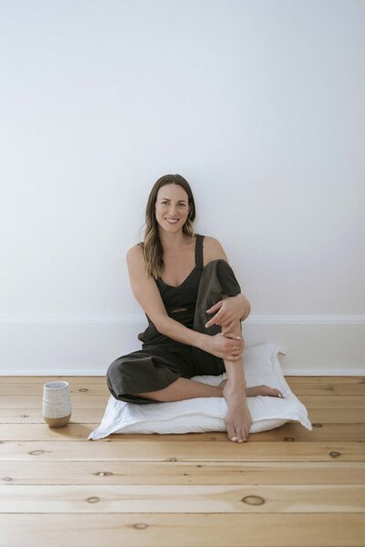Yoga and Pilates coach relaxing on a cushion with a cup of tea beside her