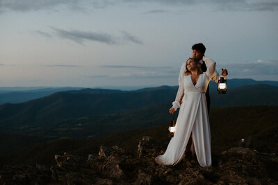 Couple at blue hour holding lanterns at a shenandoah mountain overlook on their elopement day