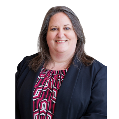 	•	“Portrait of a woman with shoulder-length brown hair, wearing a patterned red and black blouse under a black blazer. She has a friendly expression and is smiling against a white background.”