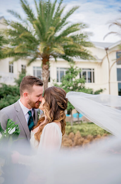 tropical wedding veil shot and couple kissing