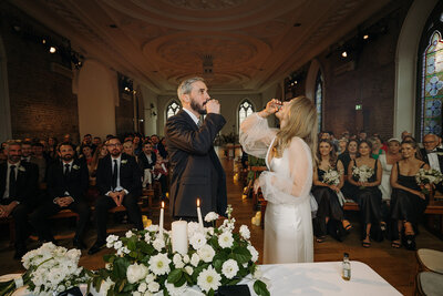 Bride and groom taking shots in front of their wedding guests at Smock Alley in Dublin, Ireland