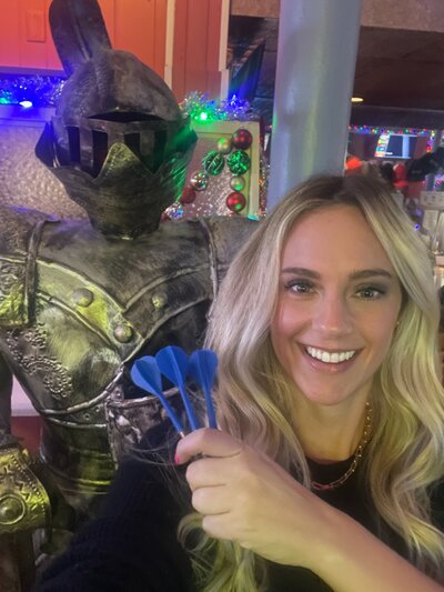 Casual photo of a woman taken in low light next to a decorative statue, representing a typical online dating profile picture before a professional session