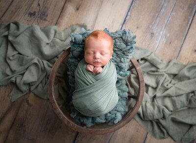 A red headed newborn wrapped in green by a Utah Newborn Photographer.