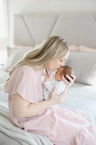mom kissing newborn baby's forehead during an in home lifestyle newborn session