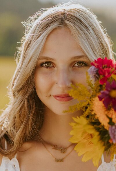 Lindzy's headshot with a bright bouquet of flowers.