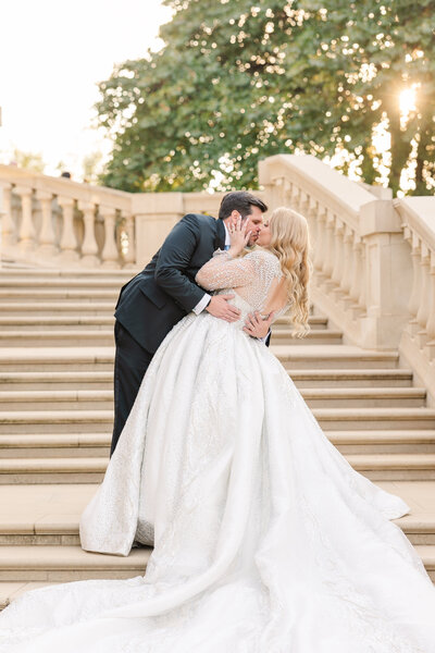 A romantic and editorial-style wedding portrait captured on the grand stone staircase in Hickory Creek, Texas. This light and airy image showcases timeless elegance and golden hour glow, perfect for couples seeking luxury wedding photography in the DFW area.