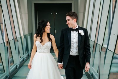 Newlyweds look at each other as they exit a building.
