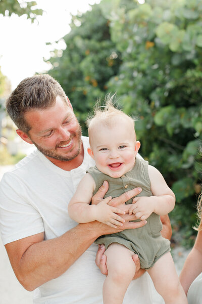 Dad holding his son smiling on the beach during their sunset family photos