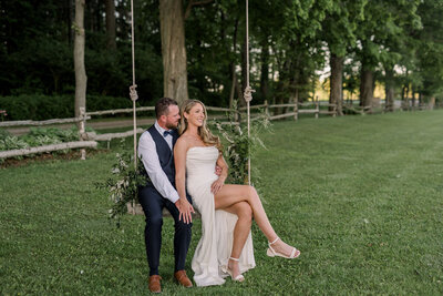 A Bride and Groom posing on a tree swing at Wheatfield Estate