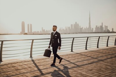 Professional man walking with a briefcase along a city boardwalk, representing business tax return services for sole proprietors, LLCs, trusts, and partnerships starting at $299 including one state return

