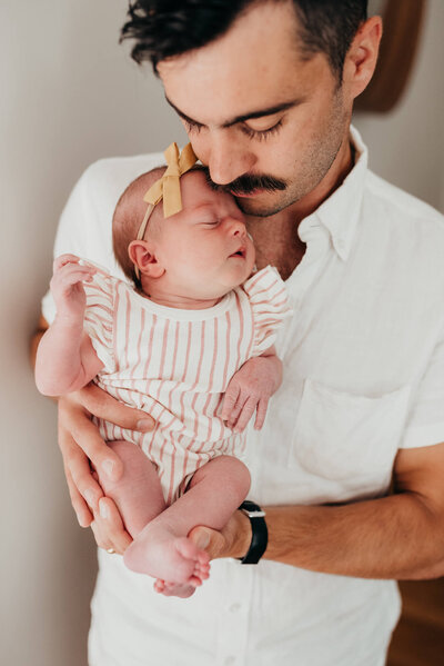 A young father holds his newborn daughter against his chest