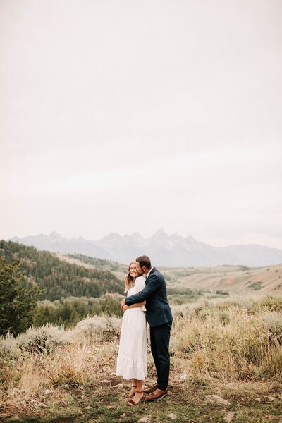 groom kissing the side of a cheek of a young bride holding gorgeous bouquet photographed by jackson hole wedding photographer adrian wayment