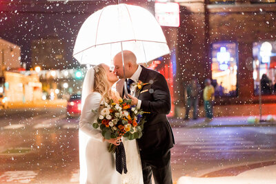bride and groom kissing in the rain under an umbrella