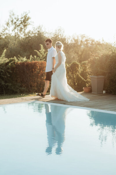 Couple walking by a swimming pool at sunset with reflection