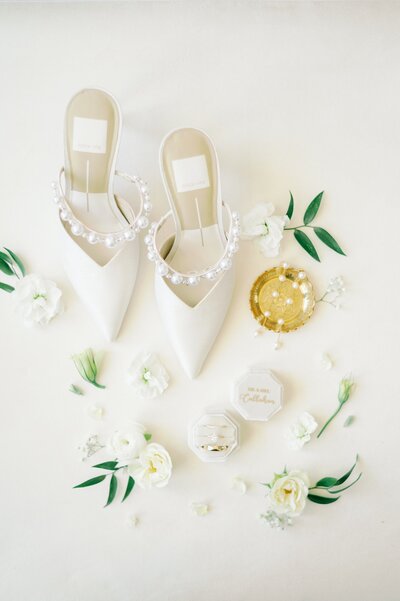 a flat lay of white, green, and gold wedding details