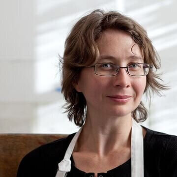 Portrait of Michelle Wilson, papermaker and educator, wearing a white apron and glasses.