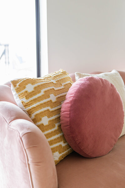 Three pillows on a pink velvet couch