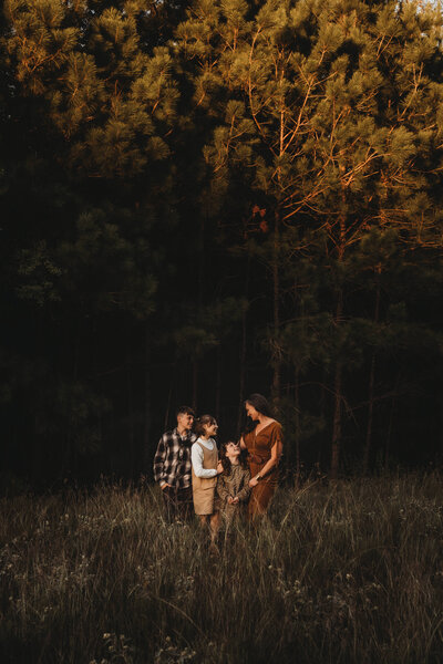 Mother hugging her children tightly during a sunset family session in The Woodlands