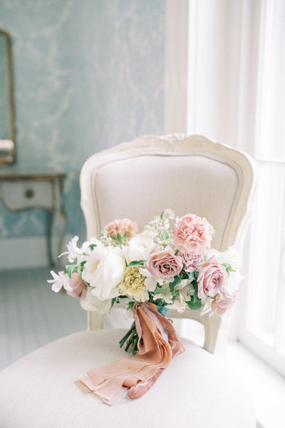 Soft blush and ivory wedding bouquet on an elegant chair