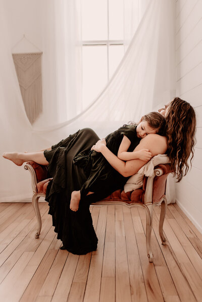 A mother holding her daughter while on a couch
