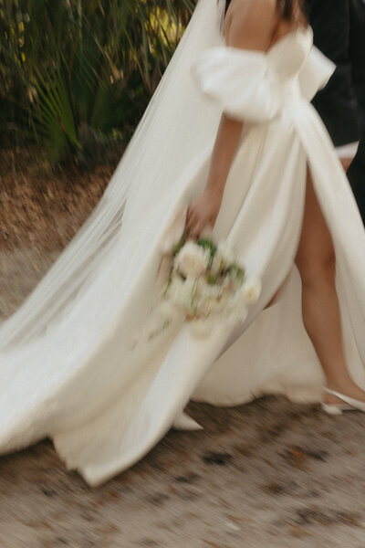 Motion shot of bride walking in her gown with bouquet in hand, showcasing luxury wedding planning services in Northeast Florida.