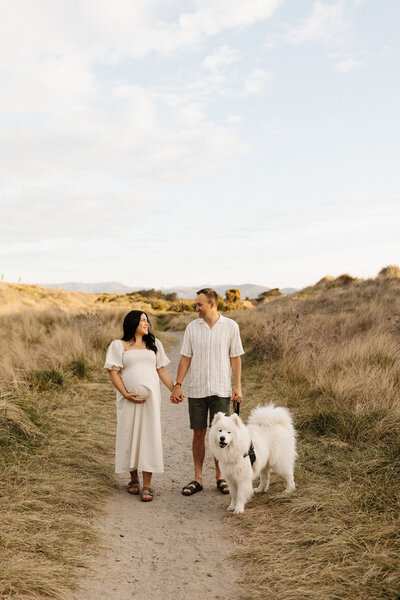 A pregnant woman and her partner pose with their dog for their maternity photoshoot with Christchurch photographer Lucy Jane Photography