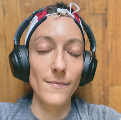 White person with short brown hair and eyes closed wearing big headphones