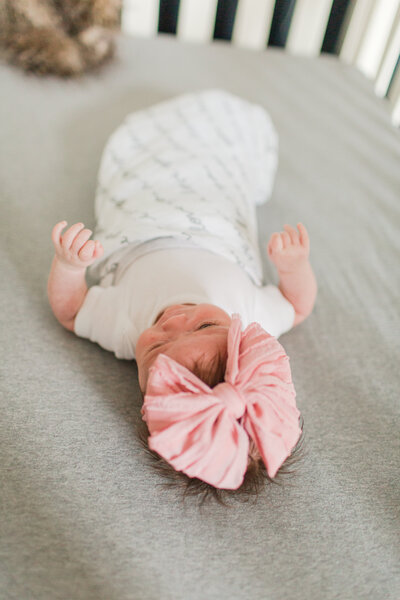 newborn baby girl pink bow headband laying in crib