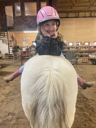 Child laughing while sitting on a horse at Spirit's Respite Ranch in Alberta.