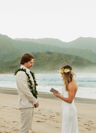 bridge and groom holding hands on beach at hanalei bay baech in kauai