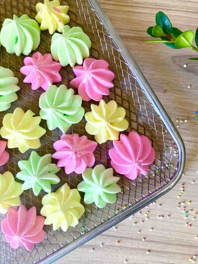 Neon green yellow and pink meringue rosettes on a  wire tray
