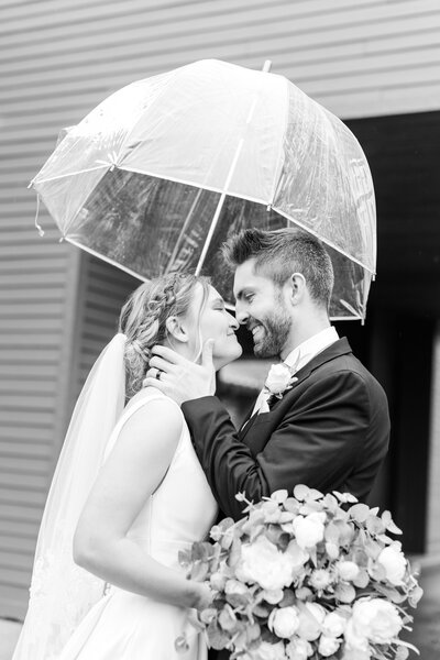groom and bride embracing under umbrella