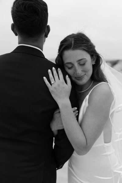 Bride gently rests her head on the groom’s arm, her eyes closed and face soft, as they stand together during their wedding.