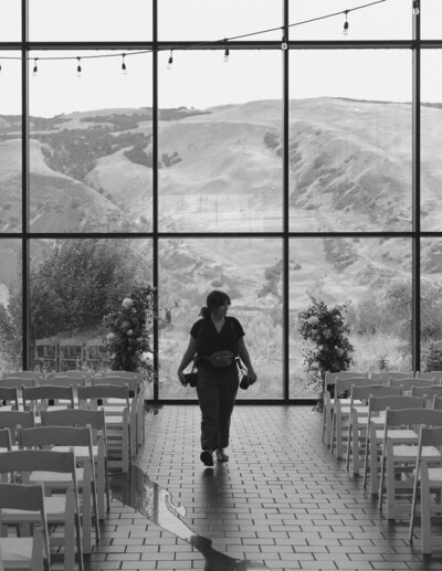 candid branding image of photographer exploring wedding venue with camera gear before ceremony