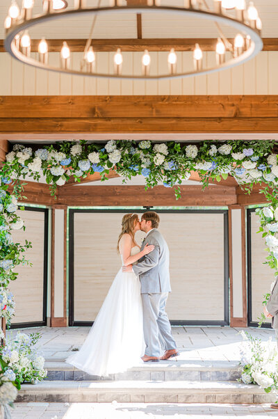 Elegant wedding ceremony floral arch designed by Leigh Florist featuring lush greenery and soft white blooms for a romantic outdoor setting