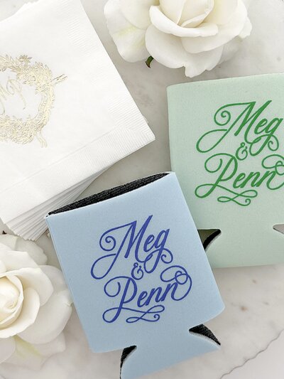Custom can holders and beverage napkins with gold embossed wedding crest.