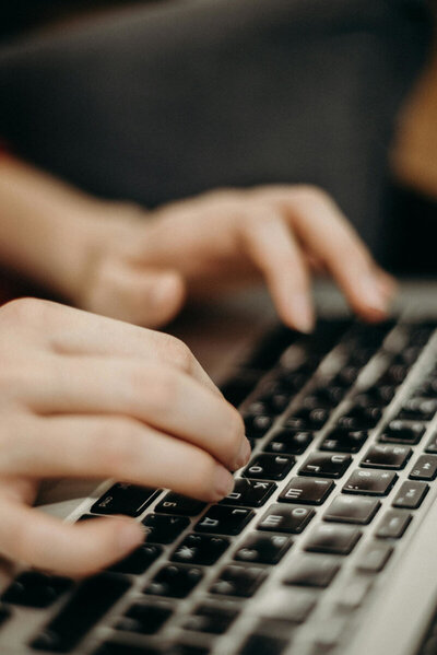 Closeup of hands typing on a laptop keyboard.