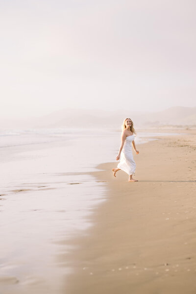 College graduate running on the beach 