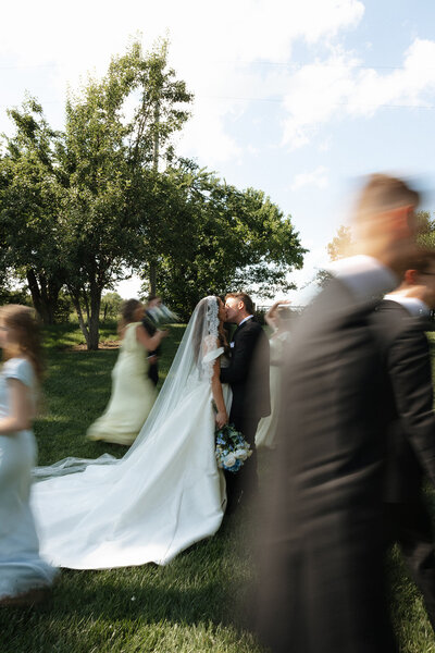 A bride and groom kissing in the middle of their wedding party at a park in Kingman Kansas.