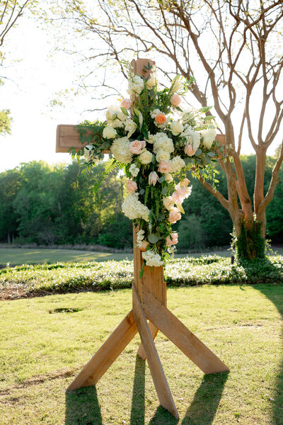wooden cross covered in flowers in grass field