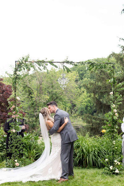 Bride and groom share their first kiss during their outdoor wedding ceremony in New Jersey